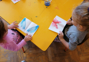 Dziewczynki otwierają kartki z utworzonym przez siebie kleksem z farby